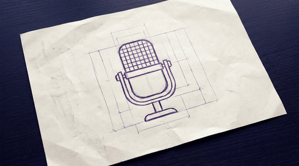 a vintage-style recording microphone, characterized by a large, upright, rectangular capsule with a front-facing grille, supported by a u-shaped yoke mount attached to a small, circular desktop stand