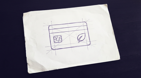 a plastic payment card, similar in size and shape to a standard credit card, featuring an embedded microchip on the left and a stylized leaf emblem on the right